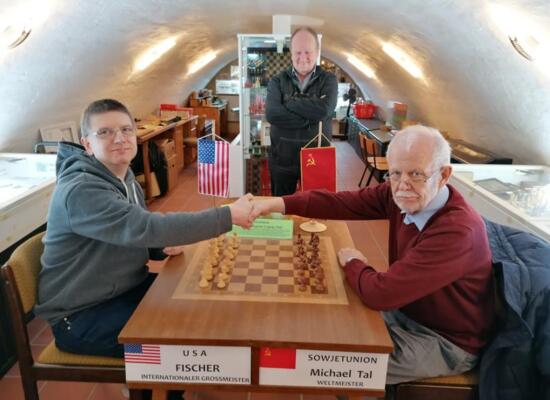 Schiedsrichterbesuch im Schachmuseum Löberitz 2022: Frank Jäger und Jürgen Kohlstädt am Olympiatisch von 1960, dahinter Roland Katz.