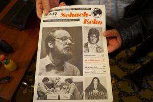 Berlin, Hübner-Simultan 2019: Matthias Kribben hält das Schach-Echo 6/1983 in der Hand, wo sein deutscher Jugendmeistertitel verkündet wurde. Viel größer ist das Foto von Robert Hübner, dem er das Heft kurz danach vorlegen wollte.